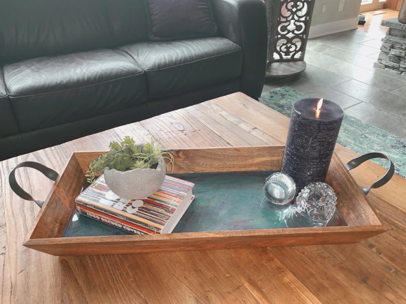 A wooden tray with candles and books on top of it.