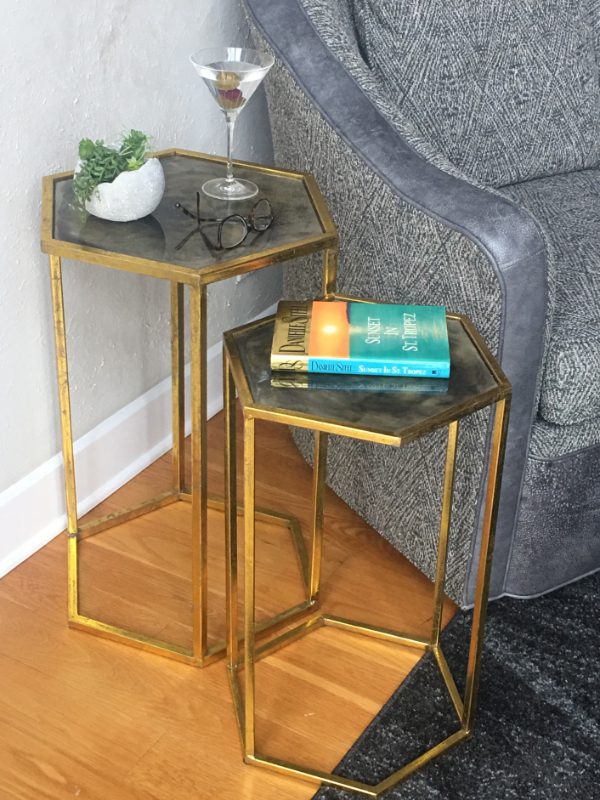 A pair of gold tables with glass tops on top.