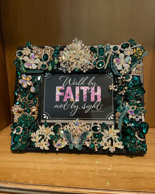 A picture frame with jewels and a quote.