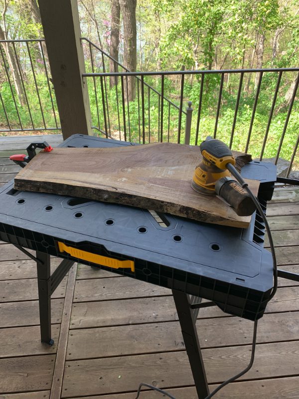 A table with a piece of wood and a yellow hand saw.