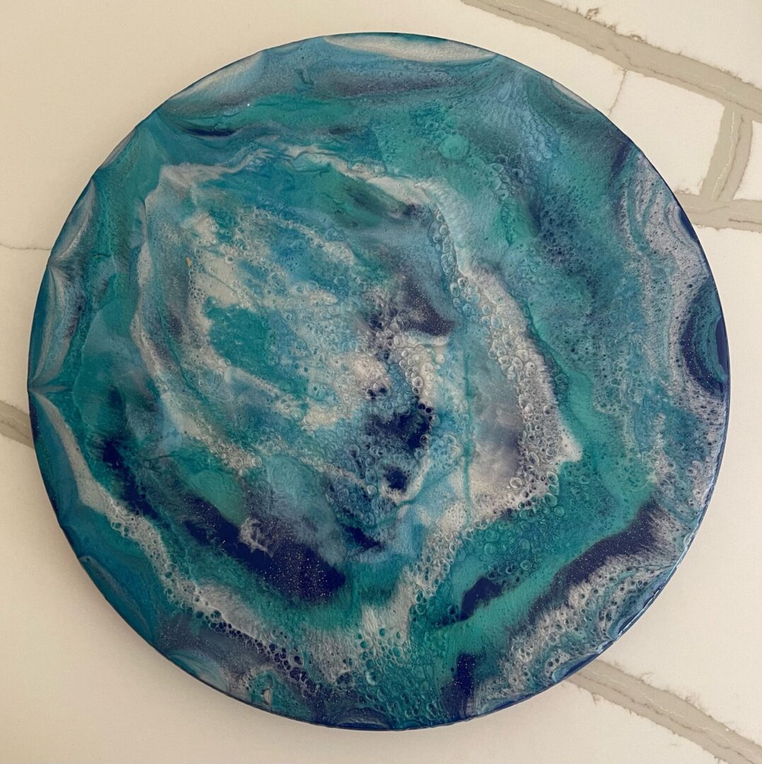 A round painting of blue and white swirls.